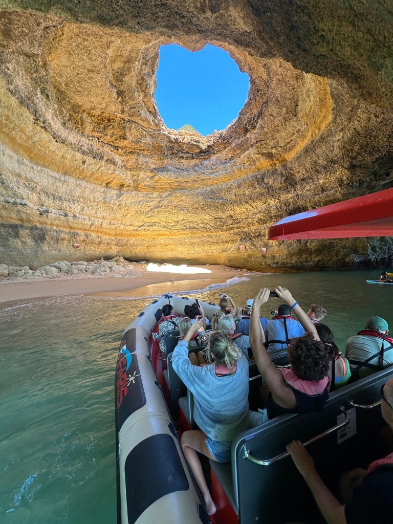 People on a boat inside a cave with a round skylight above.