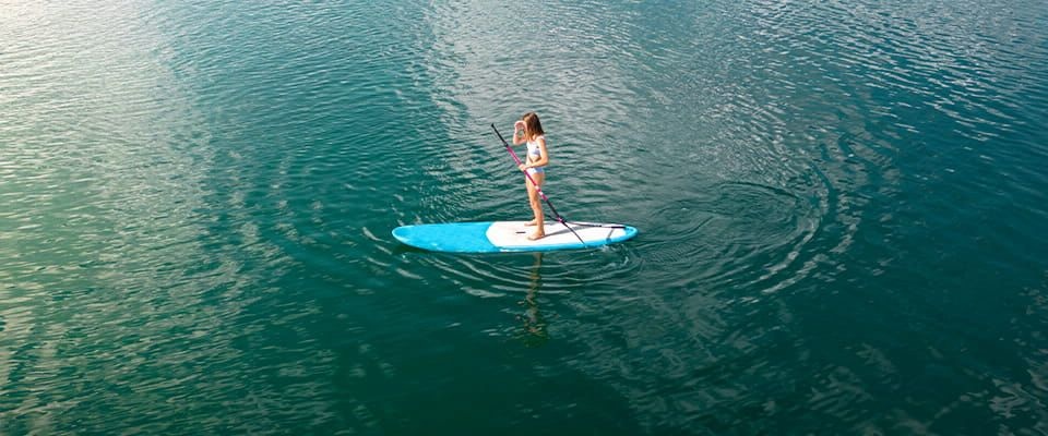 Person paddleboarding alone on a calm blue lake.