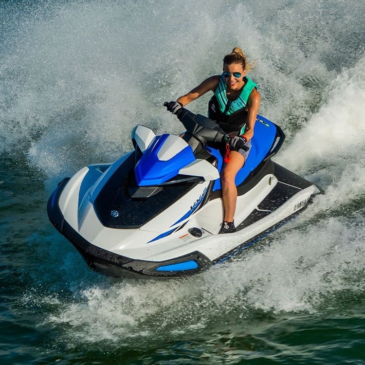 Woman riding a blue and white jet ski on the water with splashes around.