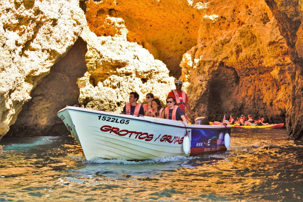 Tourists on a boat explore rocky sea caves.