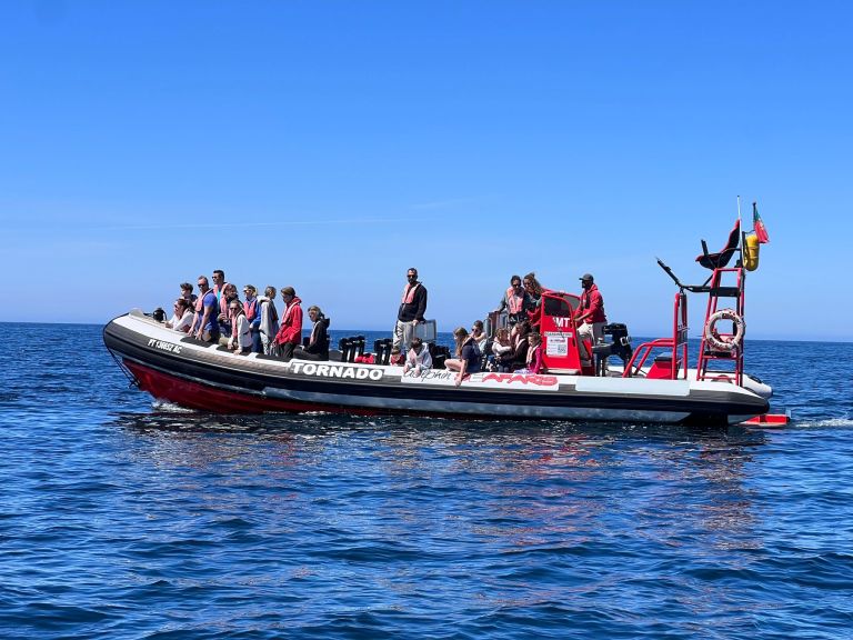 People on a red inflatable boat named Tornado on calm sea.
