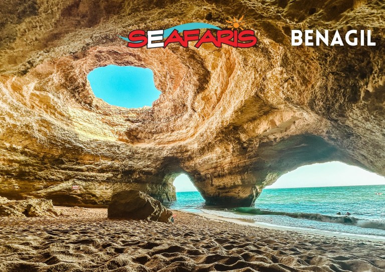 Cave interior with sea view through openings, sandy beach.