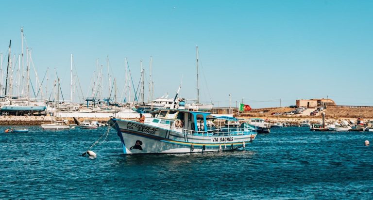Boat on water near marina with several sailboats in background.
